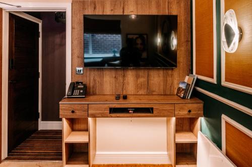 a bathroom with a wooden vanity with a television on the wall at Domo Boutique Hotel Birmingham in Birmingham
