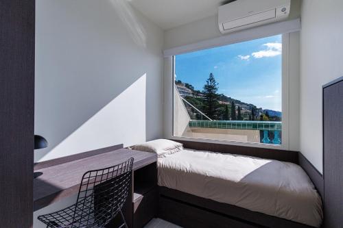 - une chambre dotée d'une fenêtre avec un lit et une chaise dans l'établissement New - sea view - splendid apartment, à Nice