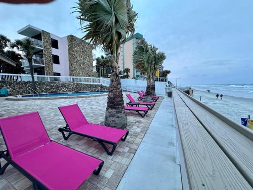 a row of pink chairs sitting next to the beach at Flamingo Inn Beachfront - Daytona Beach in Daytona Beach