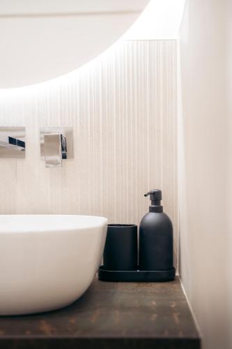 a bathroom with a sink and a bottle of soap at ROAL SUITE - Apulian luxury house - Jacuzzi & SPA in Polignano a Mare
