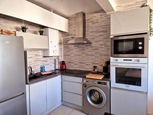 une cuisine avec des armoires blanches et une laveuse et une sécheuse dans l'établissement Le Chap'Appart, T3, à Narbonne