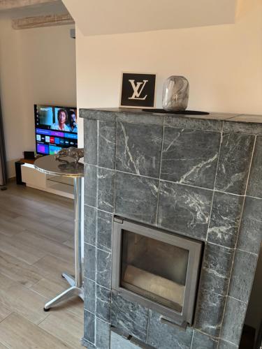 a fireplace in a living room with a table and a tv at Wood&Stone - Modernes Haus in Seenähe am Tankumsee mit Terrasse, Outdoorküche, Kamin, Homeoffice Bereich & voll ausgestatteter Küche im Naherholungsgebiet in Isenbüttel