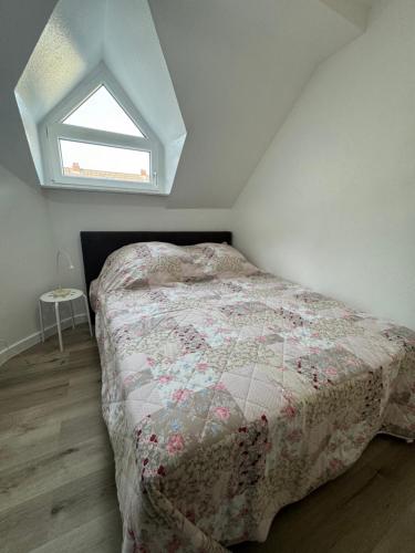 a bedroom with a bed with a quilt and a window at Friedrich Neunzehn in Andernach
