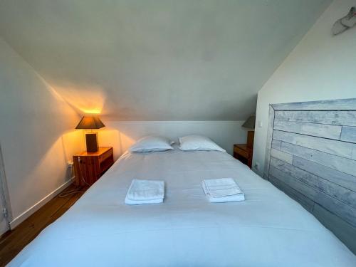 a bedroom with a large white bed with two towels at Ty Heole House in Plouézec