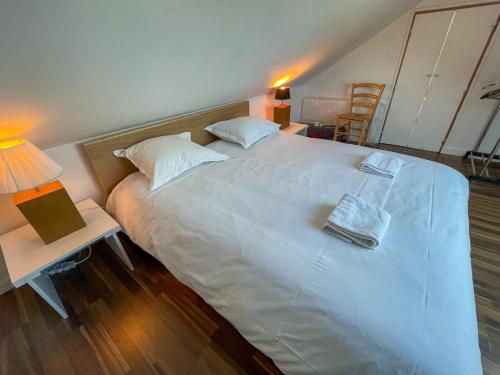 a bedroom with a large white bed with a lamp and a table at Ty Heole House in Plouézec