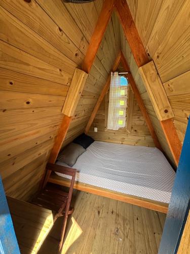 a bed in a wooden cabin with a window at Hostel São Lourenço in Bertioga