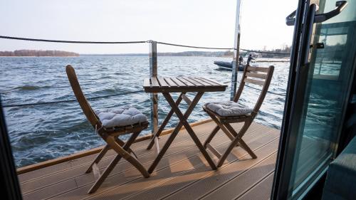 two chairs and a table on the deck of a boat at Domek na wodzie - Marina & Camping Siemiany in Siemiany