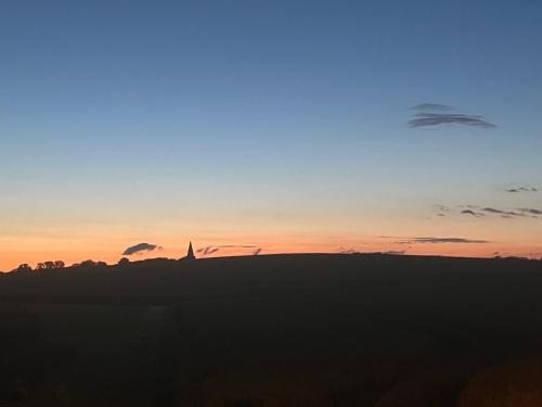a sunset over a field with a church in the background at Stallet in Ystad