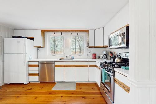 a white kitchen with wooden floors and white appliances at Lucky Number Seven in Chatham