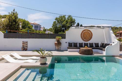 a pool with a couch and chairs next to a house at Terpsis Origin Villa in Stafylos