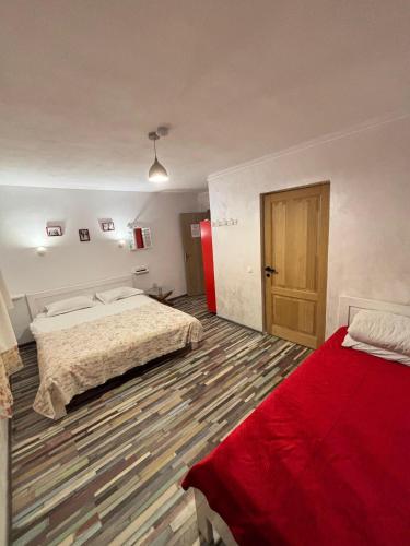 a large room with two beds and a red blanket at Pensiunea Casa Dobre in Măgura