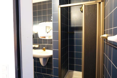 a blue tiled bathroom with a sink and a mirror at Stargaze Home Hotel in Haan