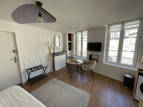 a living room with a bed and a table and a tv at Studio à 6 mins de l'hypercentre in Caen