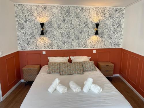 a bedroom with a bed with white pillows and a wallpaper at Studio à 6 mins de l'hypercentre in Caen
