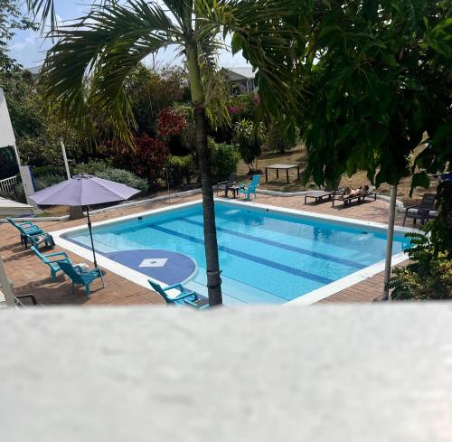 a swimming pool with a palm tree and chairs and an umbrella at Coral House SAI in El Cove
