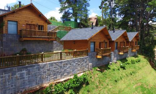 a row of wooden homes with a stone wall at Pousada Recanto dos Sonhos in Campos do Jordão