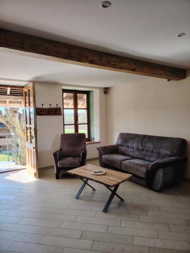 a living room with a leather couch and a coffee table at Gite Les Platanes in Lhuis