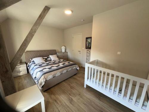 1 dormitorio con 1 cama y 1 cuna blanca en Vakantiewoning Den Landman, en Nieuwpoort