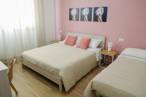 a bedroom with two beds with pink walls at Magi Rooms in Scafati