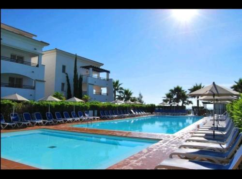 une piscine avec des chaises longues et un bâtiment dans l'établissement Amikad'o, à San-Nicolao