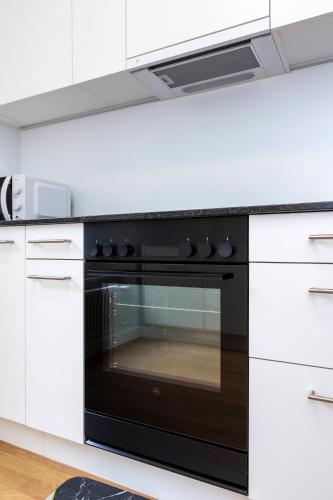 a black oven in a kitchen with white cabinets at KAYA Zurich Apartment 1B - Deluxe 2BR Downtown Apt in Zürich