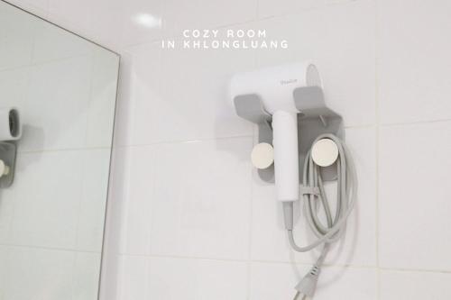a bathroom with a white toilet with a grey room in influencing at Cozy room in Khlongluang - Self Check-in in Khlong Luang