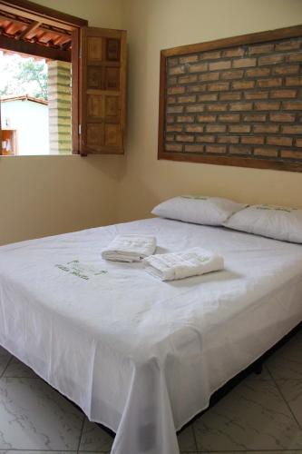 a white bed with two towels on top of it at Pousada Villa Bella in Palmeiras