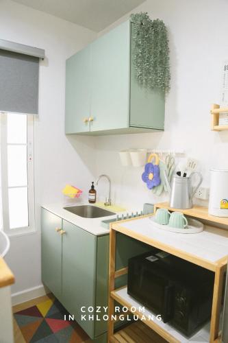 a kitchen with green cabinets and a sink at Cozy room in Khlongluang - Self Check-in in Khlong Luang