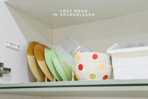 a shelf with plates and utensils on it at Cozy room in Khlongluang - Self Check-in in Khlong Luang