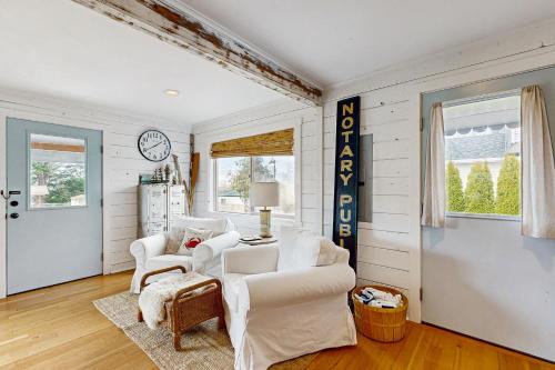 a living room with white furniture and a clock at Calm Waters in Rockaway Beach