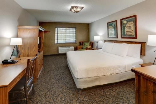 a bedroom with a large white bed and a desk at Stoney Creek Hotel St. Joseph in Saint Joseph