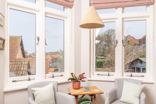 a living room with windows and a table and chairs at The Willows Boutique Stays Central Whitby in Whitby