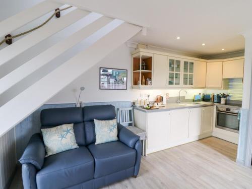 a living room with a blue couch and a kitchen at 5 The Coach House in Haverfordwest
