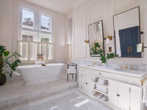 a white bathroom with a tub and two sinks at Kimpton Fitzroy London by IHG in London