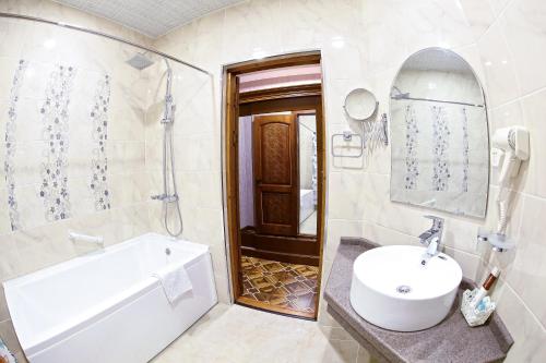 Un baño con lavabo, bañera y espejo. en Caravan plaza Hotel, en Bukhara