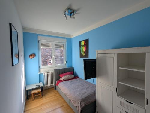 a bedroom with blue walls and a bed and a desk at Rooftop-Apartment Citylage in Offenburg