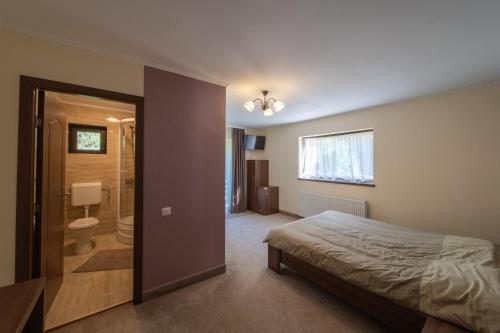 a bedroom with a bed and a bathroom at Vila Green & White in Moieciu de Sus