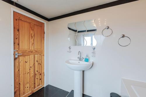 a bathroom with a sink and a wooden door at Henry House in Hartlepool
