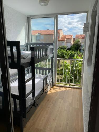 Cette chambre dispose d'un balcon avec un lit et une grande fenêtre. dans l'établissement Appartement neuf à 100m de la plage, à Marseillan