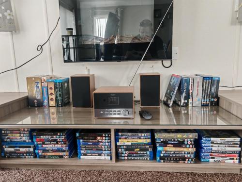 a book shelf filled with dvds and books at Manor Park Dog Friendly 2 bed, 6 berth Lodge with decking 600 Yard's From The Beach In Hunstanton in New Hunstanton