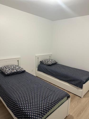 deux lits côte à côte dans une pièce dans l'établissement Colombes - Logement entier 2 chambres - Salon, à Colombes