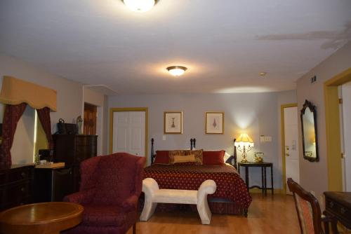 a bedroom with a bed and a chair at Auberge Wild Rose Inn in Moncton