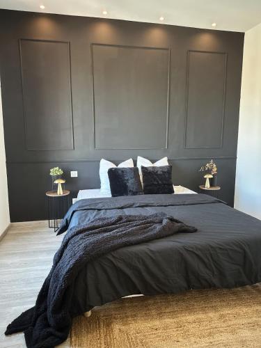 - une chambre avec un grand lit aux murs noirs dans l'établissement Au cocon des corbières - Élégance, à Lézignan-Corbières