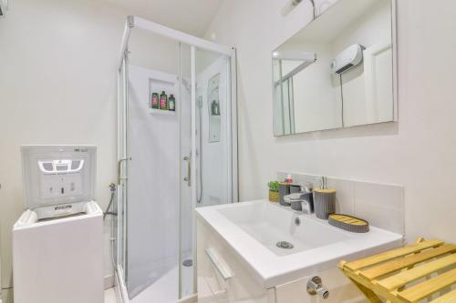 une salle de bain blanche avec un lavabo et une douche dans l'établissement La Pause Détente au pied du Stade de France, à Saint-Denis