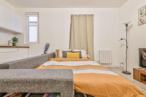 une chambre avec un lit avec une couverture orange dans l'établissement La Pause Détente au pied du Stade de France, à Saint-Denis