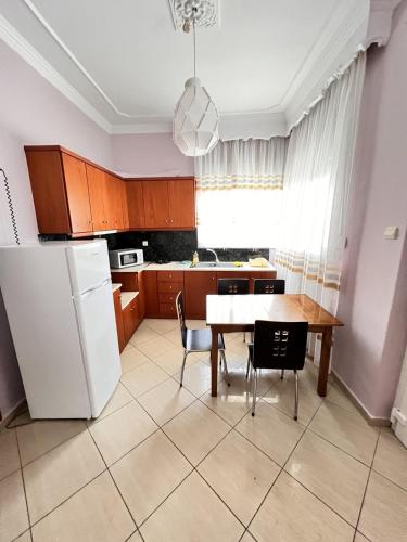 a kitchen with a table and a white refrigerator at Sand Blue Nea Peramos in Néa Péramos