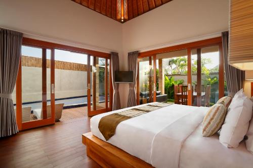 a bedroom with a large bed and sliding glass doors at Bali Nyuh Gading Villas in Seminyak