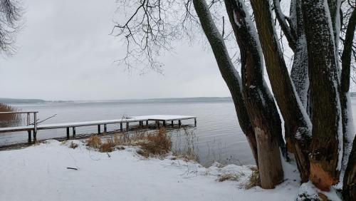a dock in the snow next to a body of water at Dom wypoczynkowy Jelonek in Swolszewice Duże