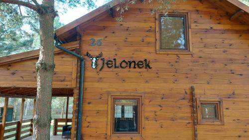a log cabin with a sign on the side of it at Dom wypoczynkowy Jelonek in Swolszewice Duże
