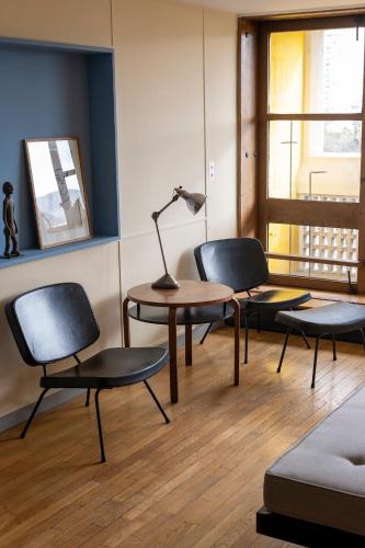 une chambre avec trois chaises, une table et une lampe dans l'établissement Le Corbusier Type B, à Marseille